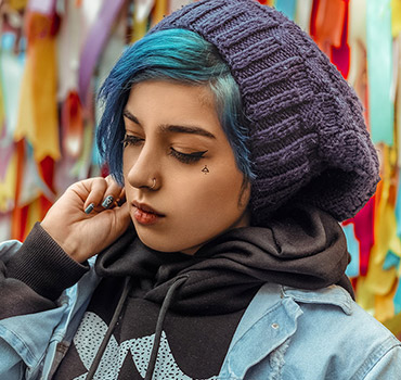 Young woman with blue hair standing in front of a colorful wall
