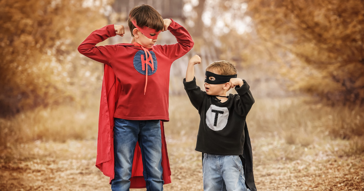 two boys wearing superhero outfits and posing
