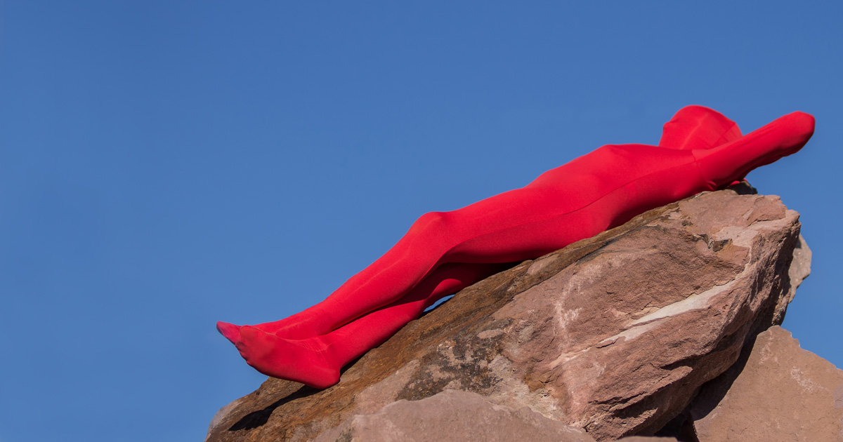 person laying down on a rock wearing a red full lycra outfit