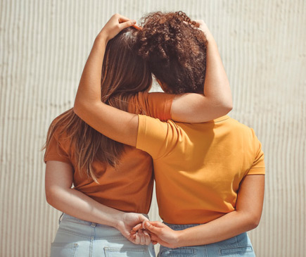 two women facing away from the camera with their arms around each other