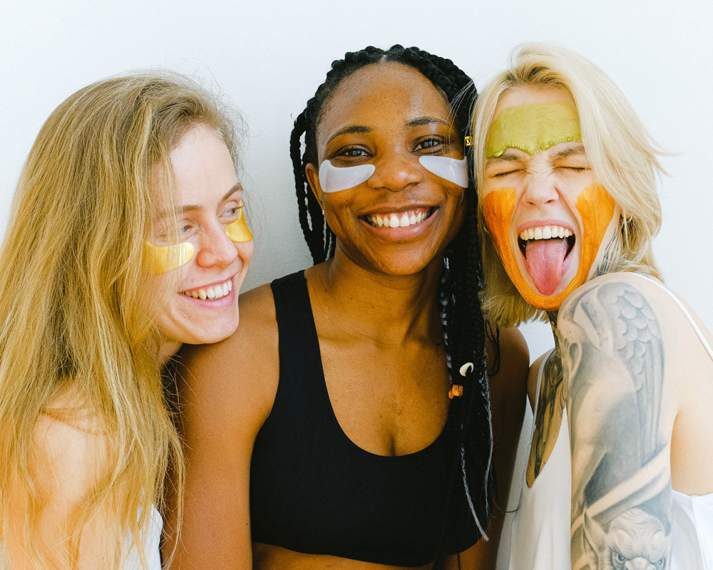 3 friends laughing and smiling with paint on their faces